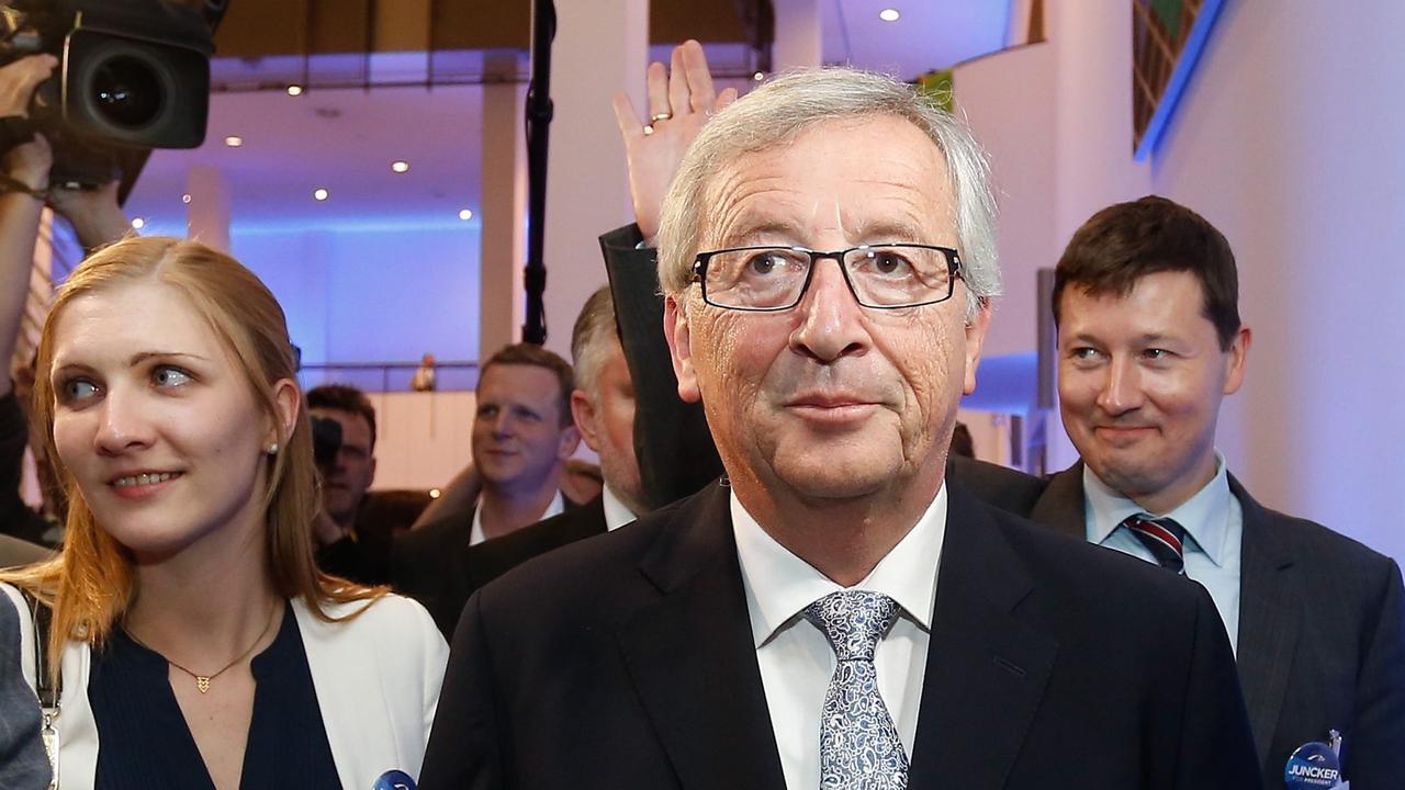 Jean-Claude Juncker am Abend der Europawahl in Brüssel. Hinter ihm stehen eine Frau und ein winkender Mann.