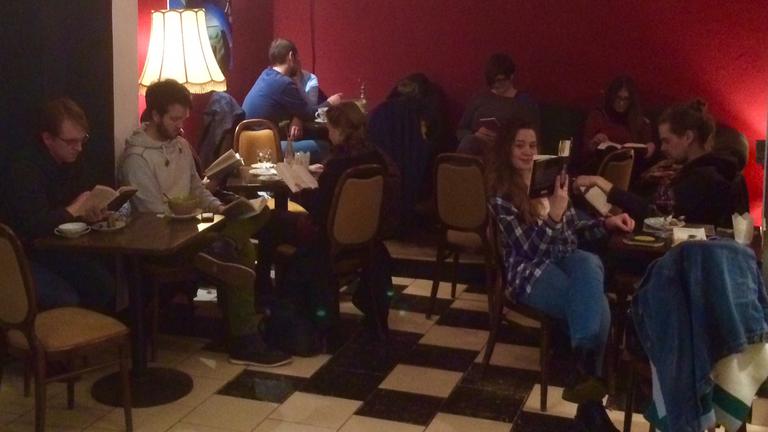 Silent-reading-party im Kieler Café Godot: Junge Menschen sitzen im Dämmerlicht und lesen.