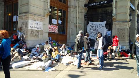 Flüchtlinge stehen, sitzen und liegen vor dem Verwaltungsgebäude des 18. Arondissements in Paris.