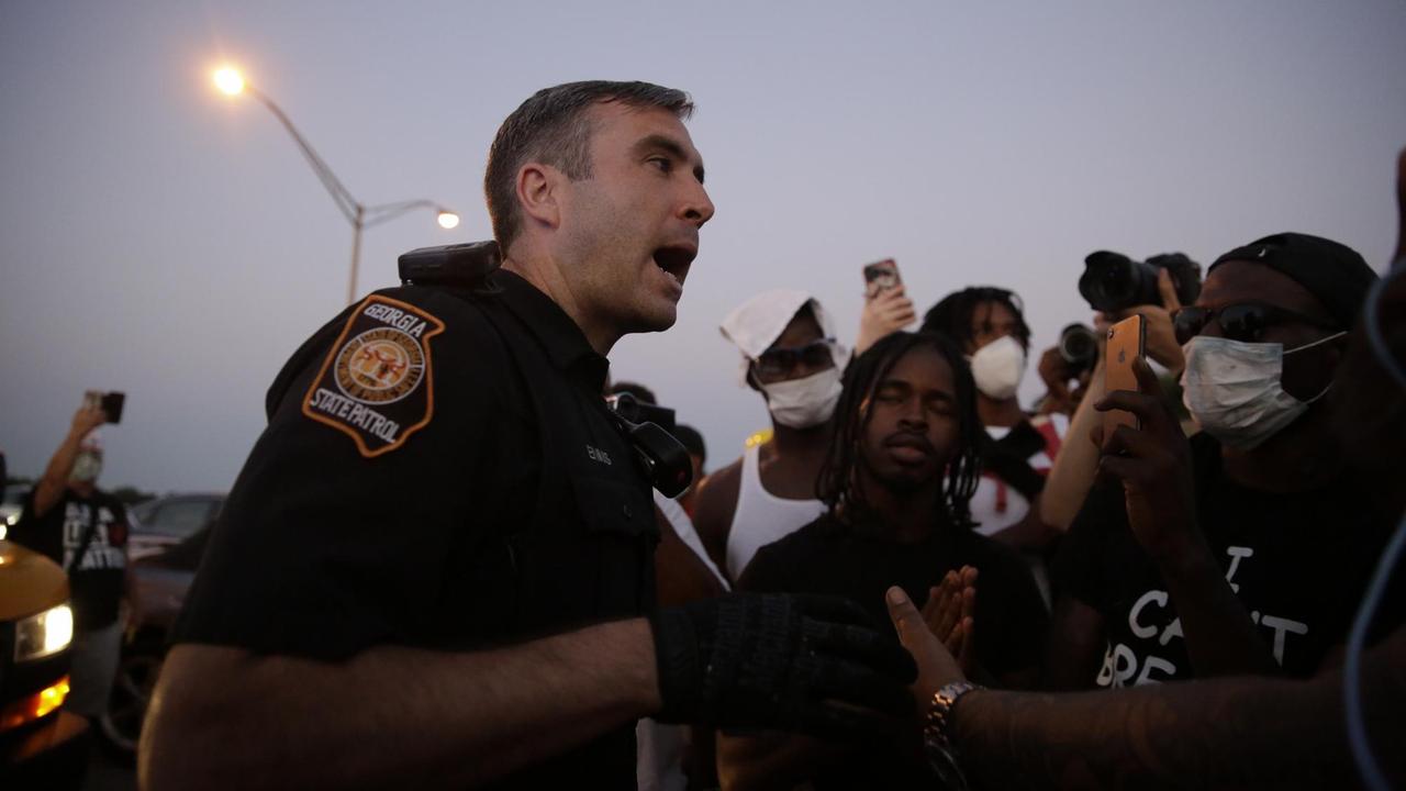 Ein aufbegrachter Polizist spricht mit Demonstranten