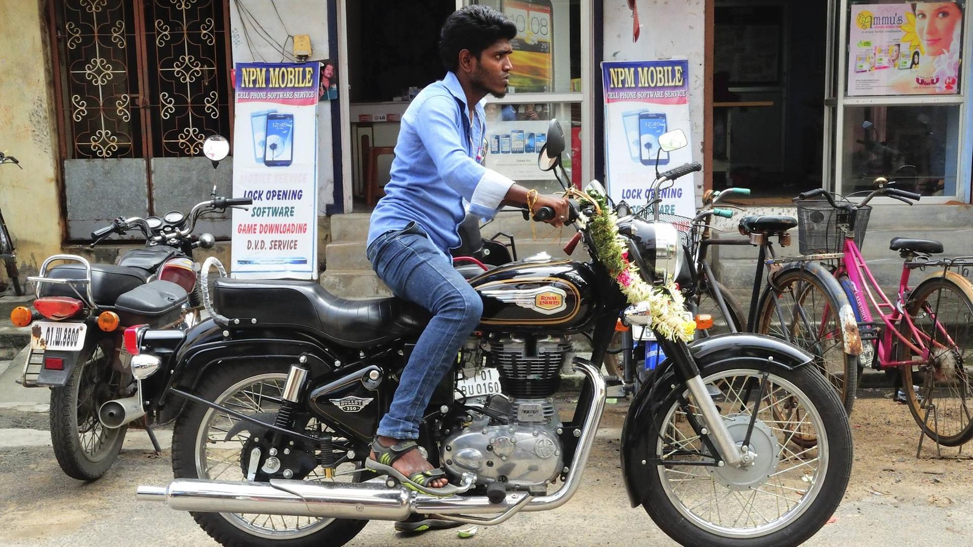 Ein Mann in Indien sitzt auf einem Royal Enfield 350 Bullet Motorrad.