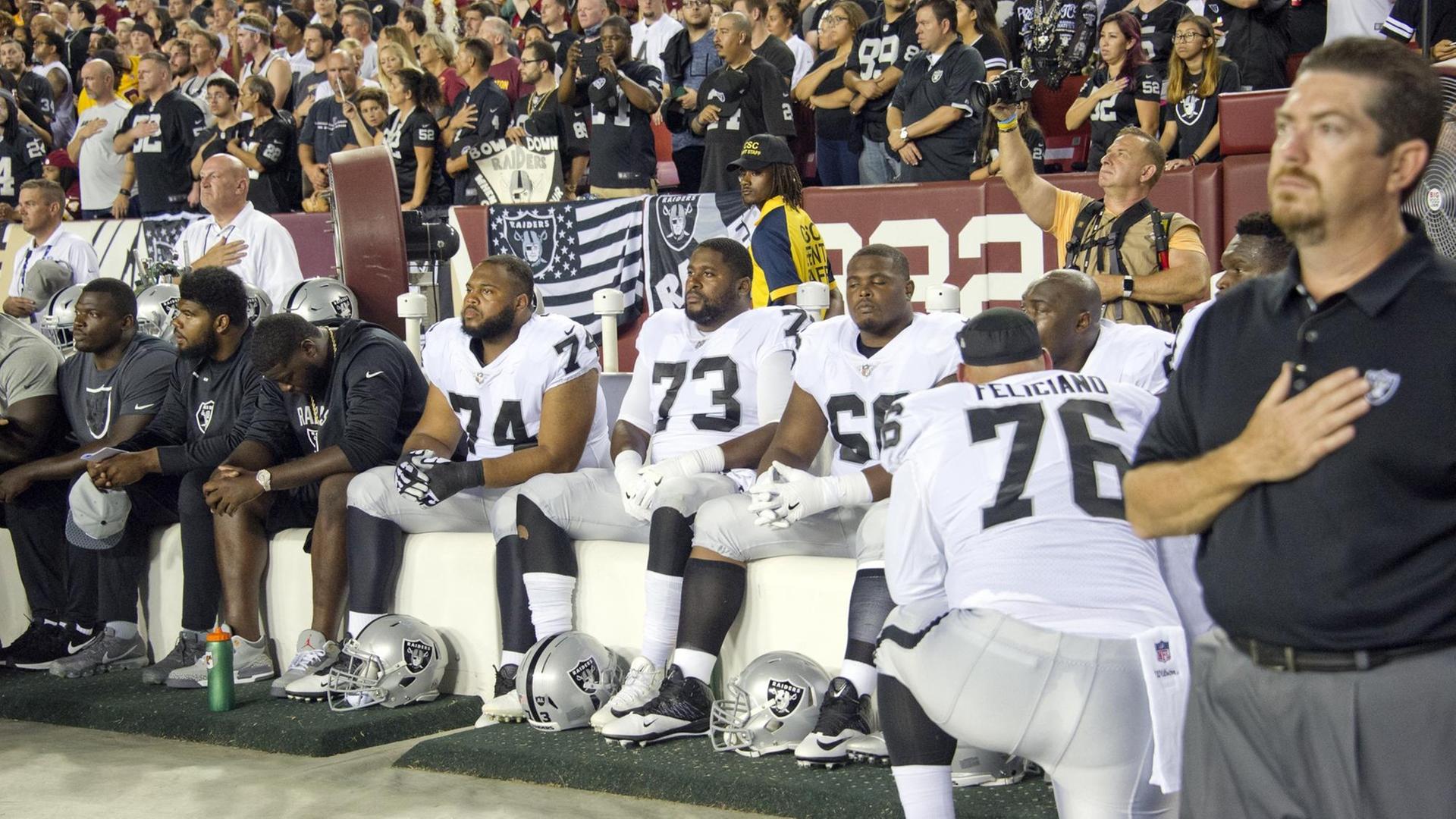 Spieler der Oakland Raiders bleiben bei der US-Hymne vor einem NFL-Spiel sitzen.
