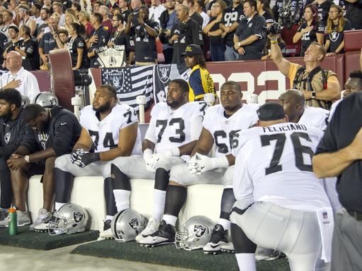 Spieler der Oakland Raiders bleiben bei der US-Hymne vor einem NFL-Spiel sitzen.