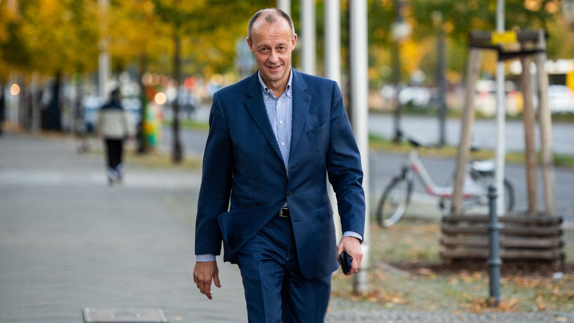 Friedrich Merz, Kandidat für den CDU-Vorsitz, geht auf einem Bürgersteig dem Betrachter entgegen.