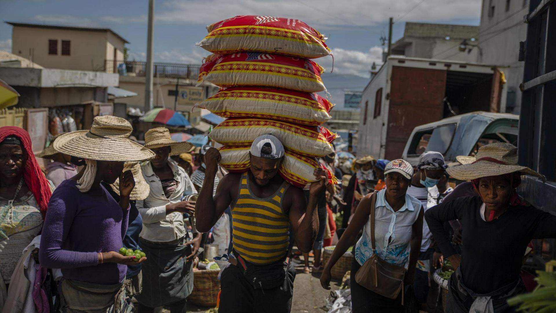 Ein Mann trägt in Haitis Hauptstadt Port-au-Prince Waren über einen Markt. Ein Mann trägt in Haitis Hauptstadt Port-au-Prince Waren über einen Markt.