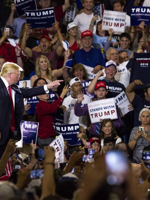 Donald Trump steht bei einer Wahlkampfveranstaltung in New Mexico am 24. Mai 2016 am Rednerpult, umringt von Anhängern, die Schilder mit Trump-Slogans in die Höhe halten.