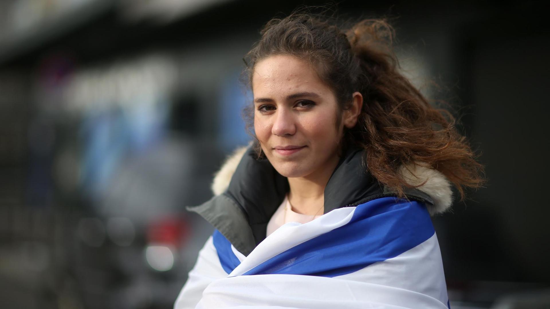 Die Pariser Jüdin Esther Bekerman besucht am 12.01.2015 in Paris (Ile-de-France) ein Geschäft, in dem zuvor ein Mann vier jüdische Geiseln erschossen hat und anschließend von der Polizei getötet worden ist, und hat sich dabei die Fahne von Israel umgehangen.