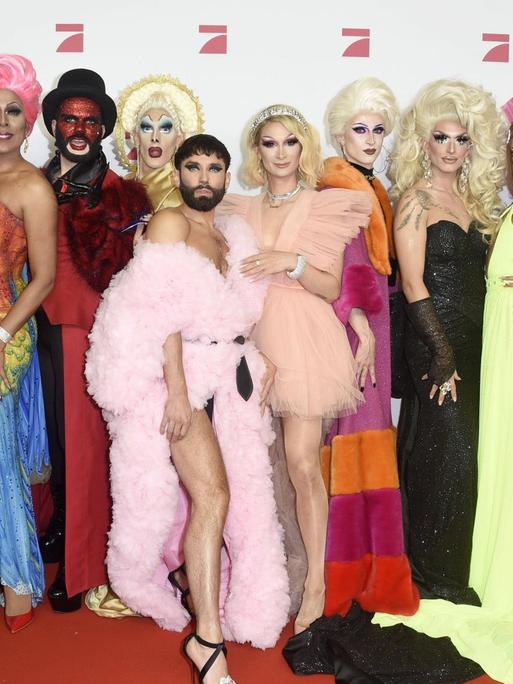 Eine Gruppe Dragqueens stehen auf dem Roten Teppich