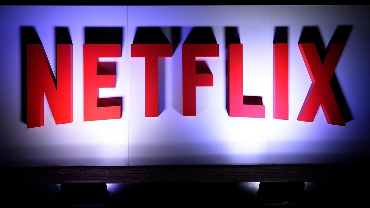 Das Firmenlogo des Streaminganbieters Netflix in großen, roten, dreidimensionalen Buchstaben an einer weißen Wand, von unten angestrahlt.