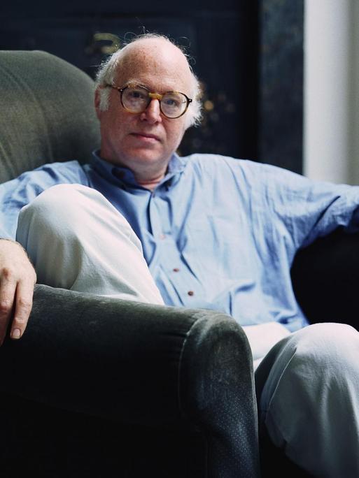 Auf dem Bild ist der Soziologe Richard Sennett zu sehen. Er sitzt in einem bequemen Stuhl und trägt ein blaues Jeanshemd