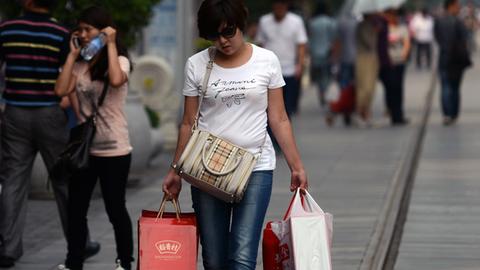 Eine Frau mit Einkaufstüten in einer Einkaufsstraße in Peking.