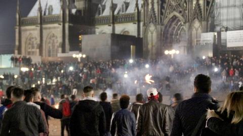 Menschengruppen vor der Kulisse des Kölner Doms, dazwischen Rauchschwaden.