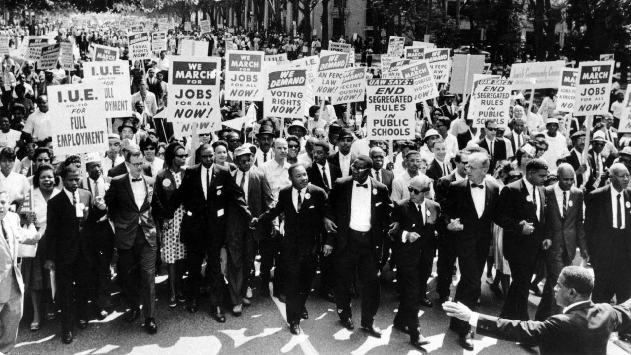 Beim "March on Washington for Jobs and Freedom" (1963) ist eine große Menschenmenge zu sehen, die Schilder mit ihren Forderungen halten. In der ersten Reihe Martin Luther King Jr. (vorne, 7.v.re.).