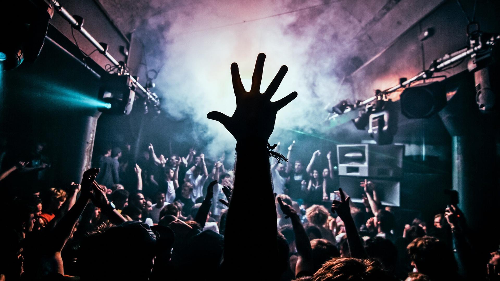 Eine erhobene Hand in einer Menschenmenge auf einer Party.