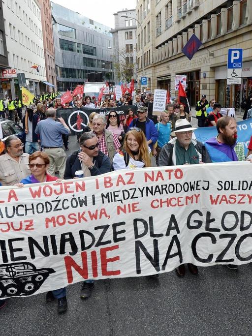 In Warschau demonstrieren Menschen am Samstag gegen den Nato-Gipfel. Sieht halten ein Schild mit der Aufschrift: "Geld gegen den Hunger, nicht für Panzer"