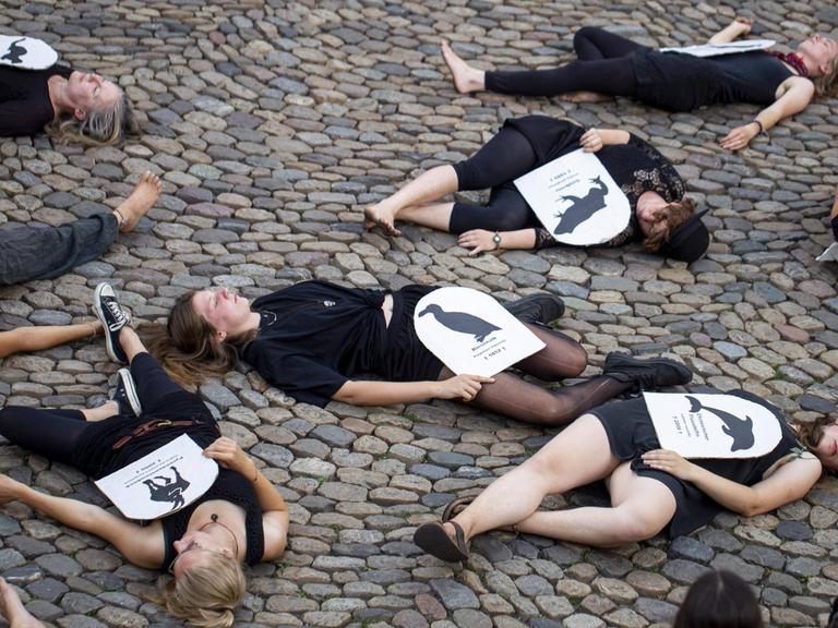 Mehrere junge Menschen liegen auf dem Boden des Augustinerplatzes und haben ein Blatt Papier mit einer aufgedruckten Tierart auf sich liegen.