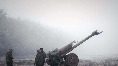 Separatisten im Osten der Ukraine stehen neben einer Artillerie-Kanone.