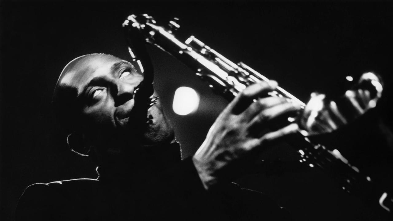 Schwarz-Weiß-Aufnahme von Sonny Rollins bei einem Auftritt mit seinem Saxophon mit starken hell-dunkel-Kontrasten.