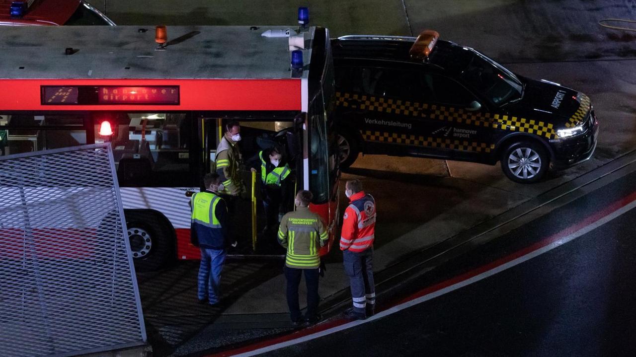 Einsatzkräfte stehen an und in einem Bus der Flughafenfeuerwehr auf dem Gelände des Flughafens Hannover-Langenhagen. 