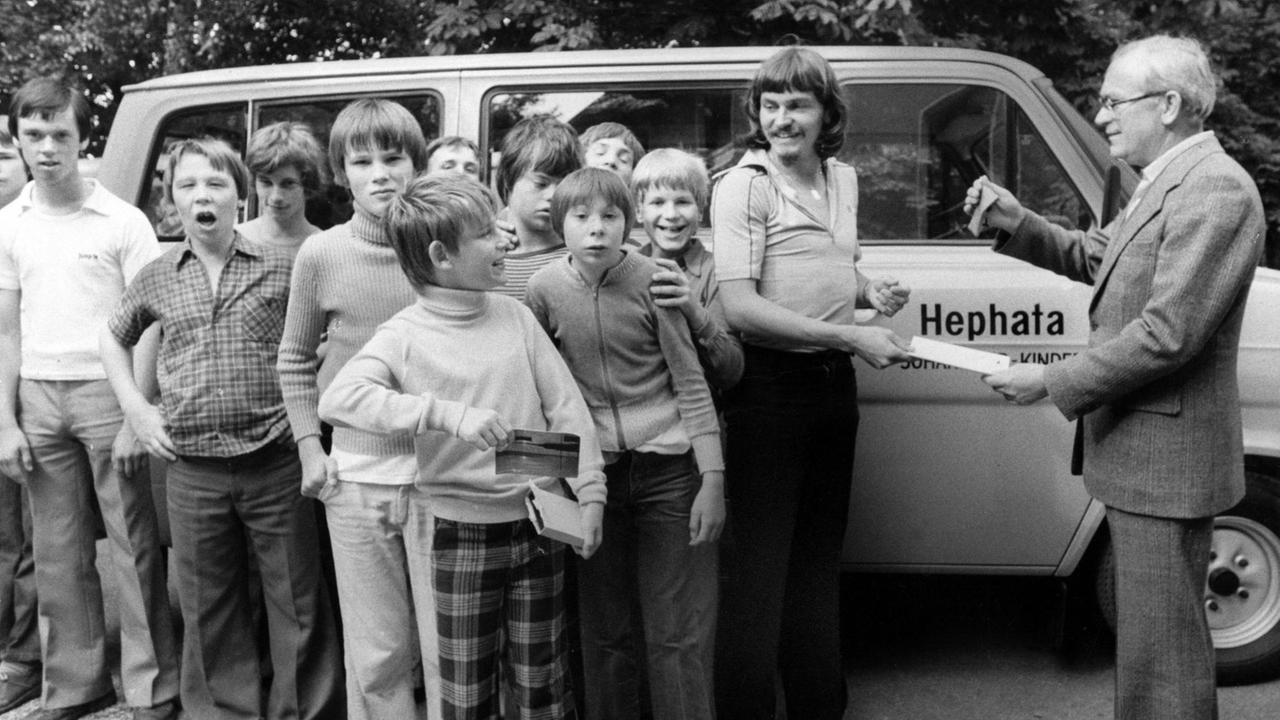 Ewald Lienen 1979 mit geistig und körperlich behinderten Kindern vor einem kleinen Bus.