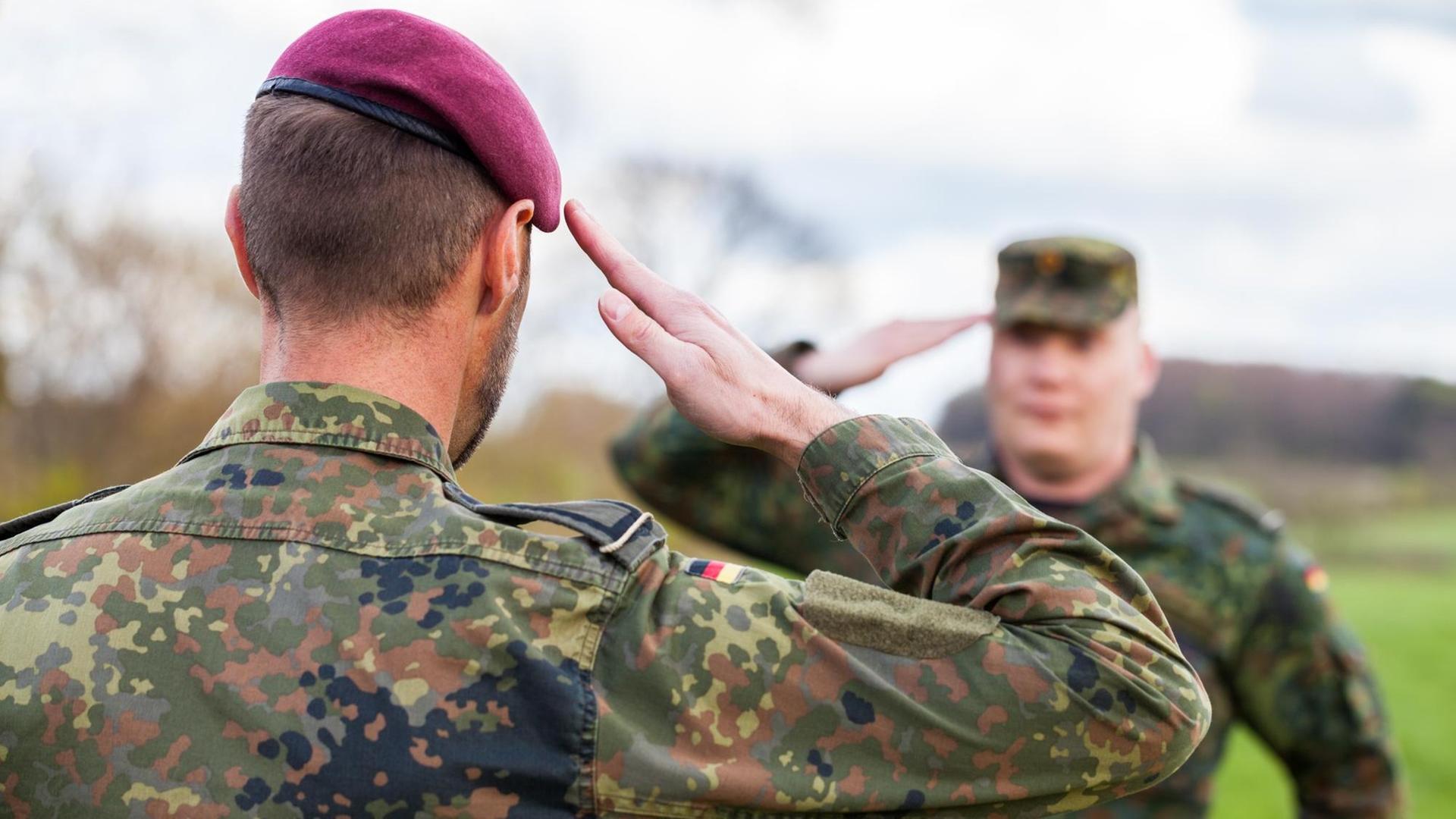 Zwei deutsche Soldaten der Bundeswehr salutieren einander.