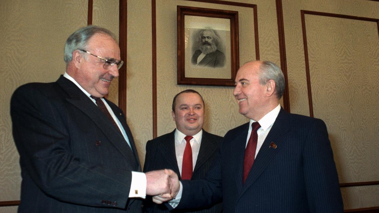Der deutsche Bundeskanzler Helmut Kohl (links) und der sowjetische Staatschef Michail Gorbatschow geben sich unter einem Porträt von Karl Marx die Hände.