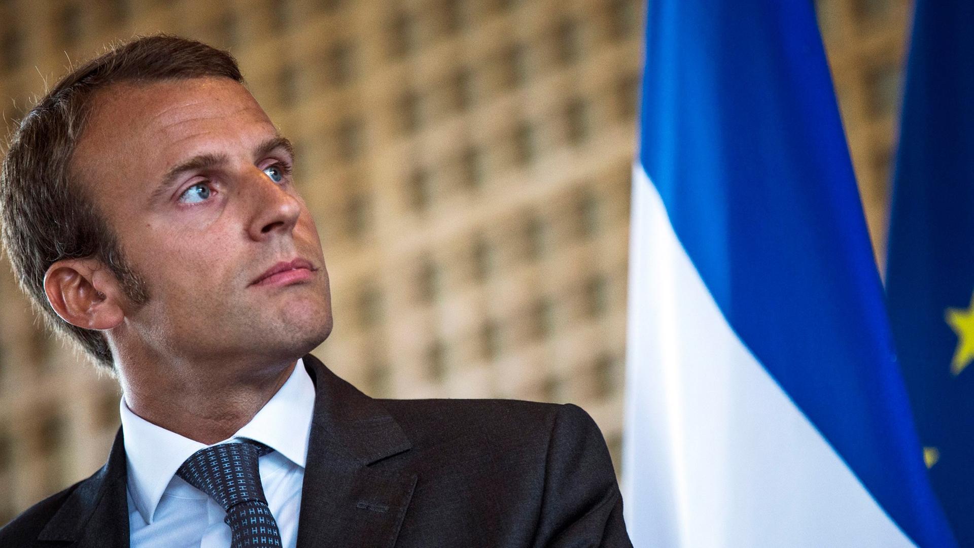 Wirtschafts-Minister Macron steht neben einer Frankreich-Fahne
