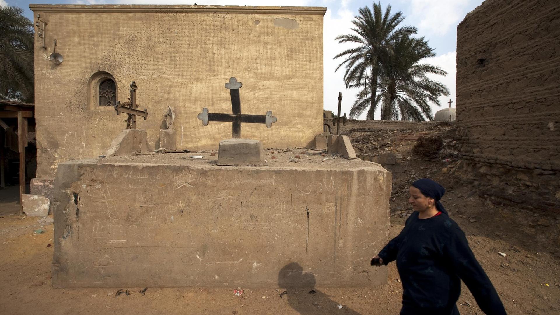 Eine koptische Frau läuft auf dem Friedhof des Koptenviertels in Kairo an einer Grabstätte vorbei (Aufnahme vom 21.1.2010).