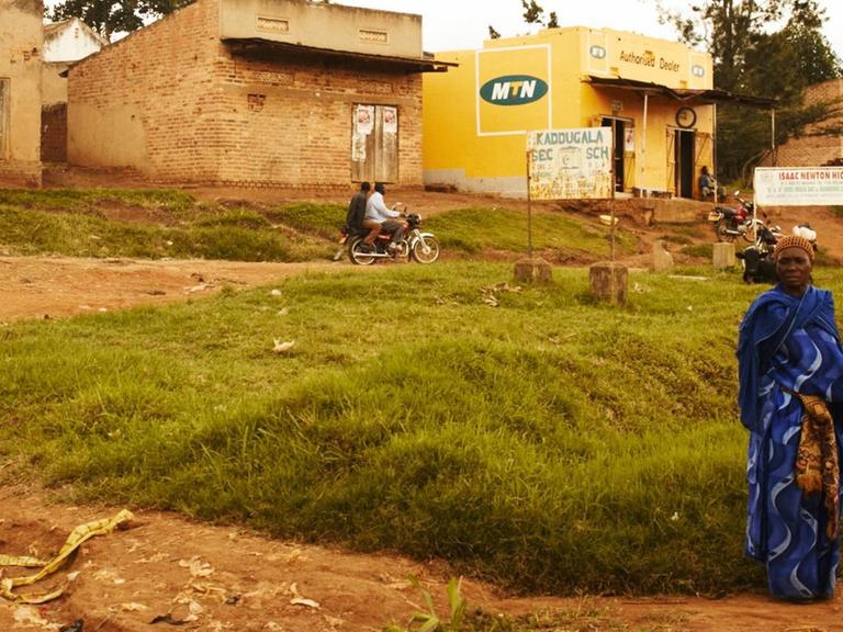 Eine Frau steht in Kampala/Uganda am Straßenrand