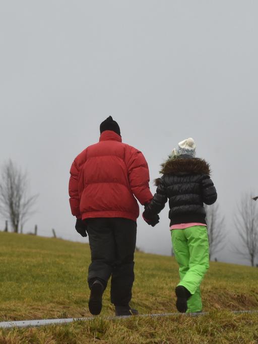 Eine Urlauberfamilie geht am bei stürmischen Regenwetter im hessischen Willingen spazieren.