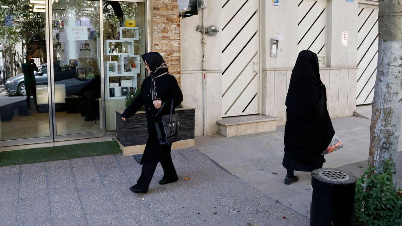 Zwei Frauen gehen in traditioneller Kleidung durch eine Straße in der iranischen Hauptstadt Teheran.