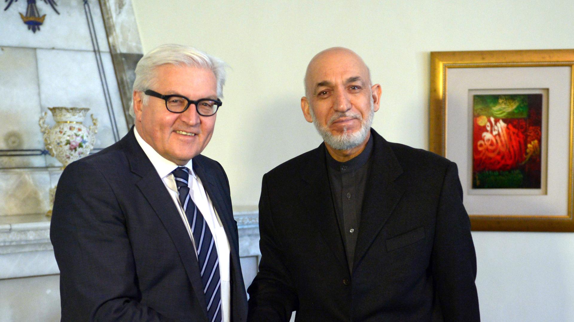 Außenminister Frank-Walter Steinmeier (SPD) und Afghanistans Präsident Hamid Karsai schütteln sich die Hände und schauen dabei in die Kamera.