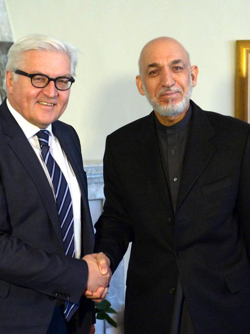 Außenminister Frank-Walter Steinmeier (SPD) und Afghanistans Präsident Hamid Karsai schütteln sich die Hände und schauen dabei in die Kamera.