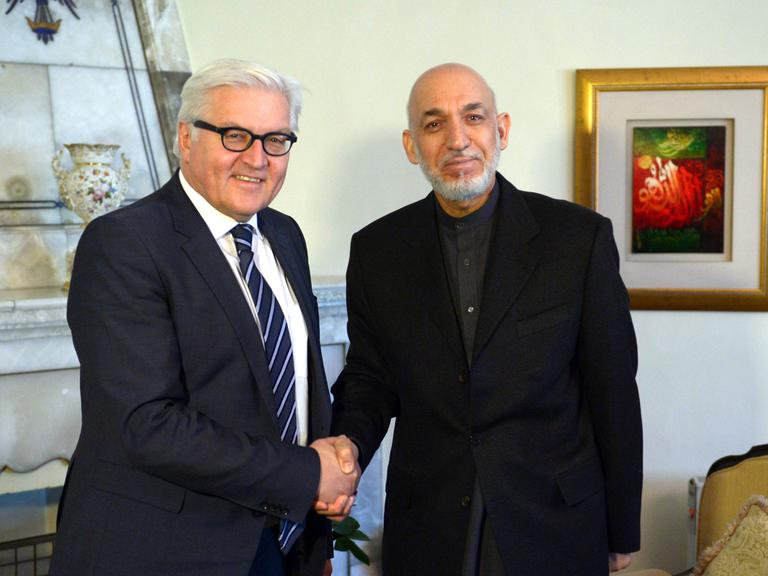 Außenminister Frank-Walter Steinmeier (SPD) und Afghanistans Präsident Hamid Karsai schütteln sich die Hände und schauen dabei in die Kamera.