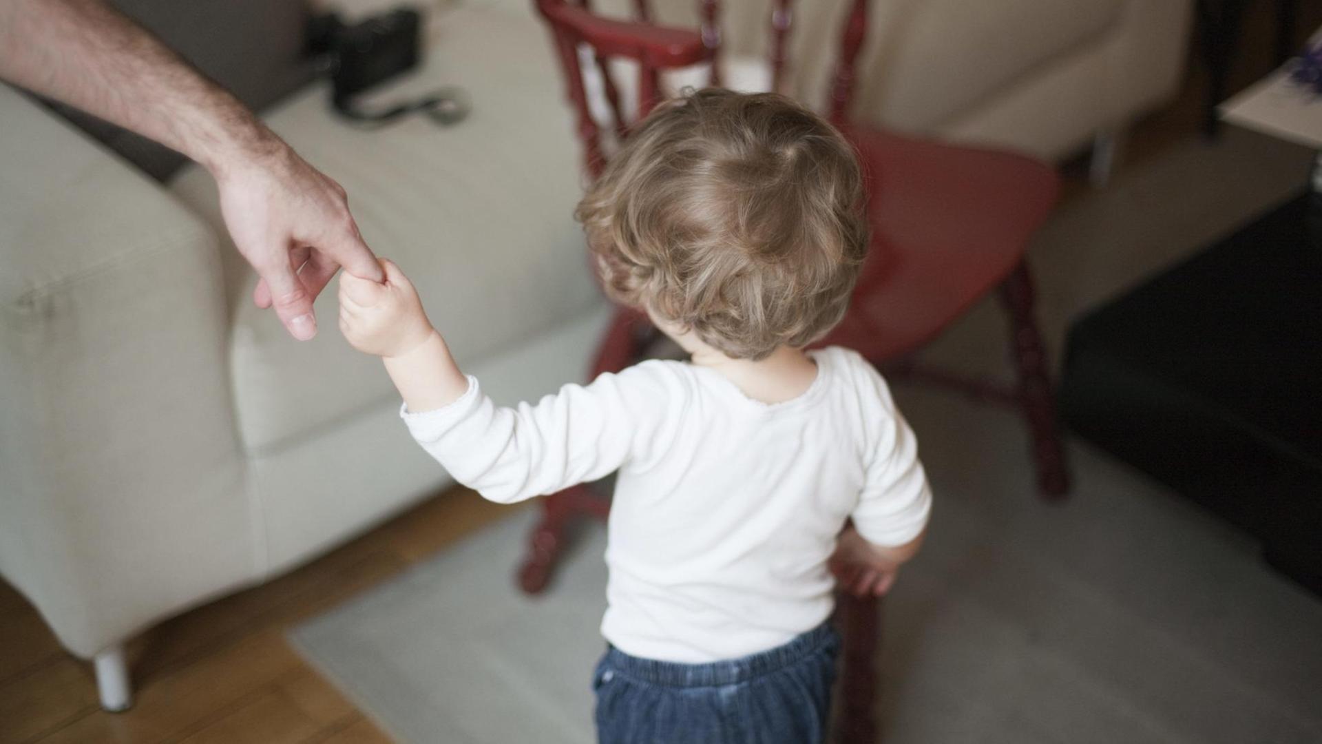 Mann hält ein Kind an der Hand