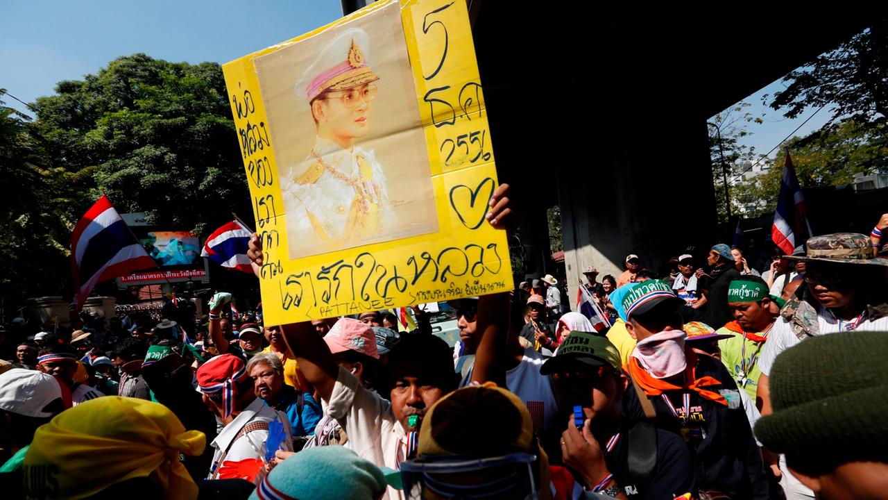 epa03975912 Anti-government protesters hold up a portrait of King Bhumibol outside the Royal Thai Police headquarters in Bangkok, Thailand, 04 December 2013. Anti-government protesters cleaned up the streets and made a peaceful march towards the Royal Tha