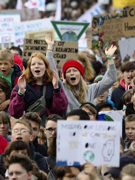 Eine große Gruppe von Menschen. Einzelne halten Schilder in die Höhe, auf denen Botschaften für Klimaschutz stehen.