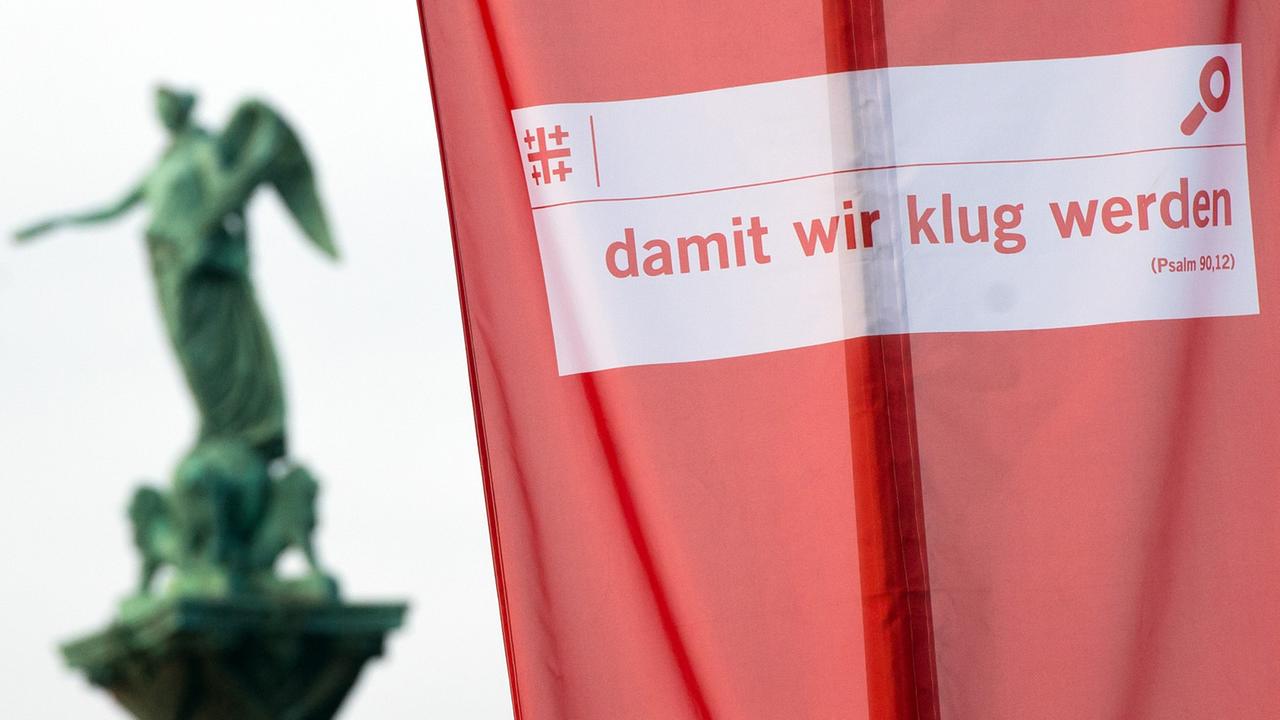 Die Flagge zum 35. Evangelischen Kirchentag mit der Aufschrift "damit wir klug werden" hängt am Schlossplatz in Stuttgart.