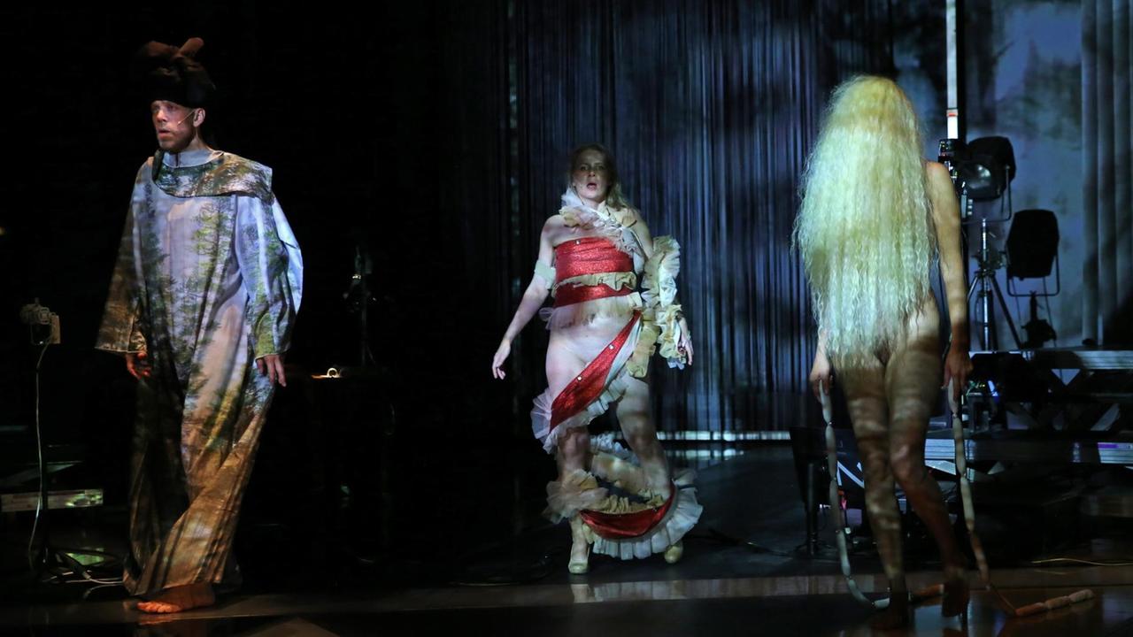 Szenenfoto von "Hexploitation" des Performance-Kollektivs She She Pop. Drei Performer laufen über die dunkel gehaltene Bühne.
