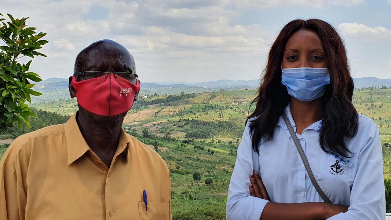Unternehmerin Liliane Sengyunwe und ein Mitarbeiter. Sie stehen draußen vor blauem Himmel und tragen eine Maske.