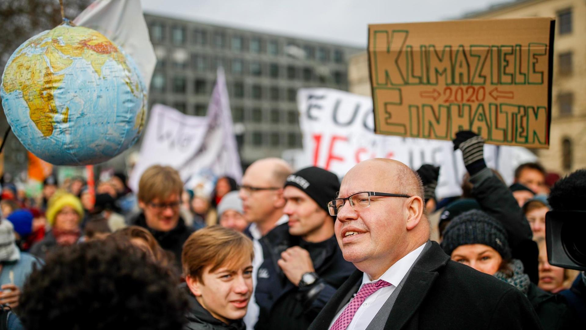 Bundeswirtschaftsminister Altmaier schaut auf die Plakate von Demonstranten für mehr Klimaschutz.
