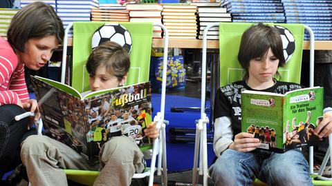 Eine Frau sieht sich auf der Buchmesse in Leipzig mit einem Kind in der Kinderbuchhandlung Fußballbücher an