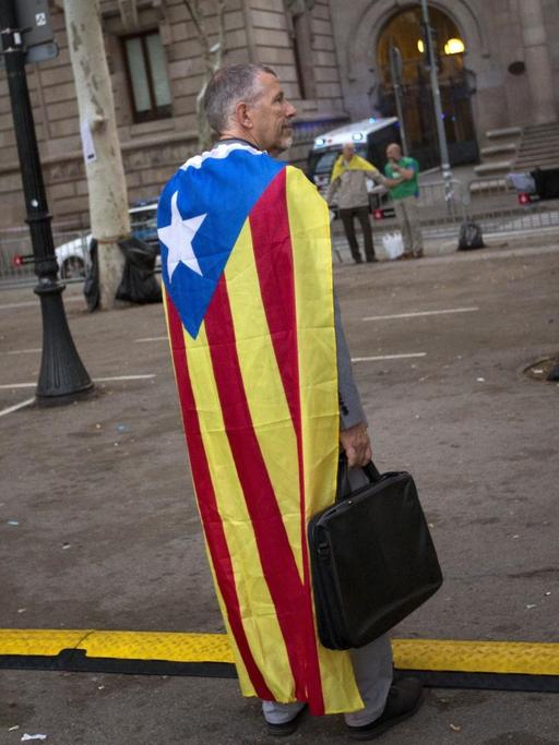 Ein Mann, bekleidet mit einer "Estelada", einer Unabhängigkeits-Fahne, vor dem katalanischen Justizgebäude in Barcelona/Spanien am 22.09.2017.