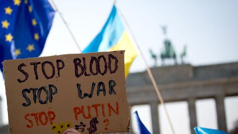 Im Rahmen einer Solidaritätsaktion für die Menschen in der Ukraine halten Menschen Plakate am Brandenburger Tor hoch.