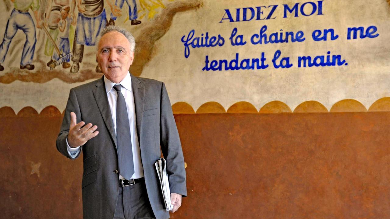 Der Soziologe Alain Chouraqui, Präsident der Stiftung "Camp des Milles", steht vor einer Wand in der Gedenkstätte.