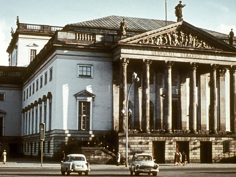 Das Opernhaus am Berliner Boulevard "Unter den Linden" in den 70-er Jahren fotografiert, in einem Moment, als einige Autos der Zeit am geweißten Gebäude vorbei fahren.