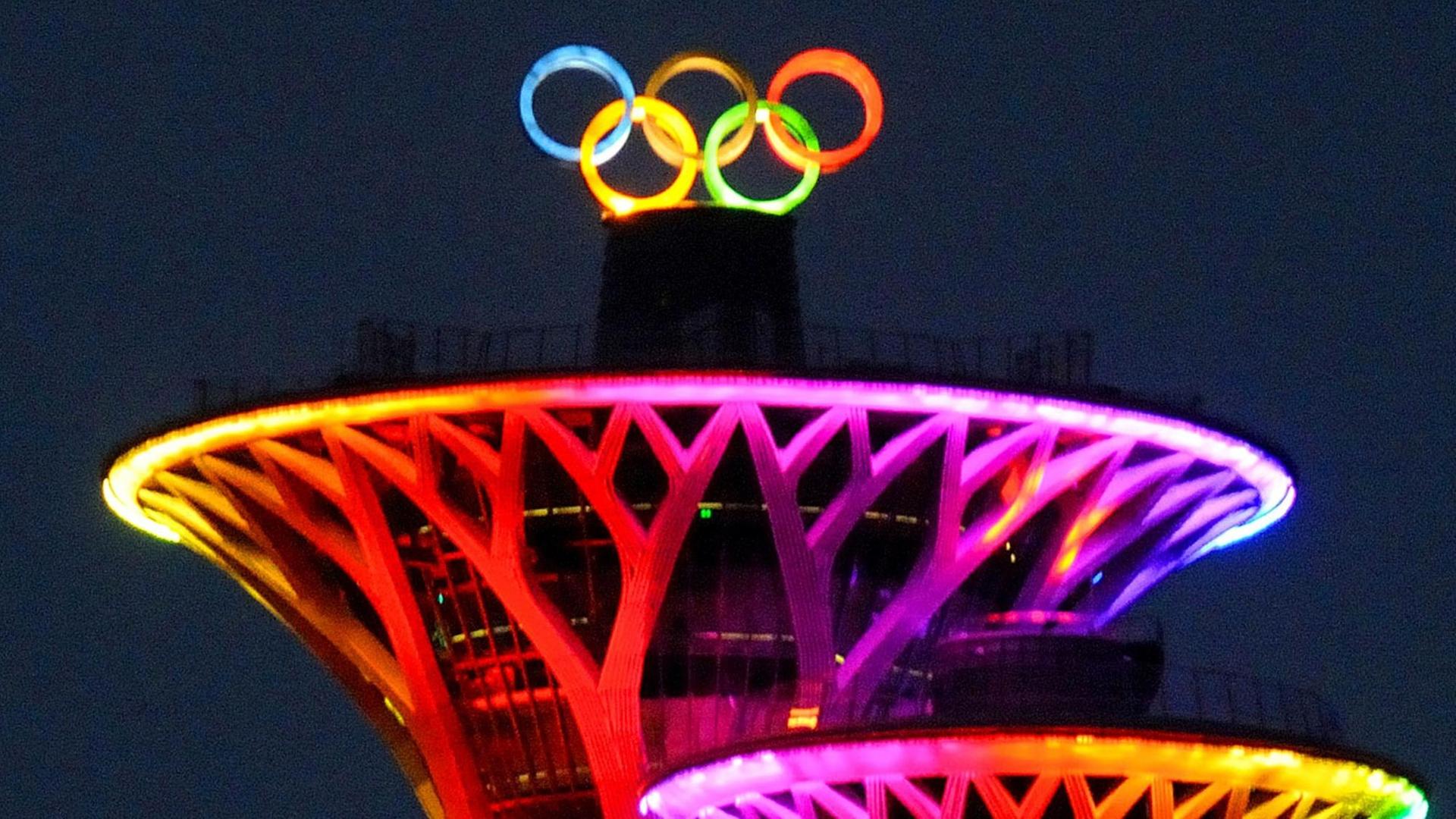 Die Olympischen Ringe leuchten bunt auf den Olympia-Türmen in Peking, der Haupt-Stadt von China.