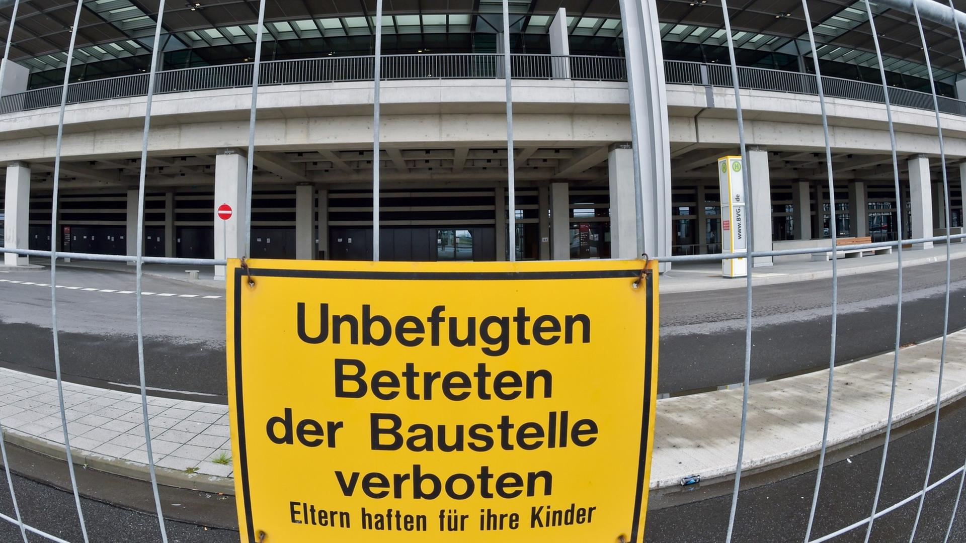 Ein Bauzaun mit einem Schild "Unbefugten Betreten der Baustelle verboten", dahinter das Terminalgebäude.
