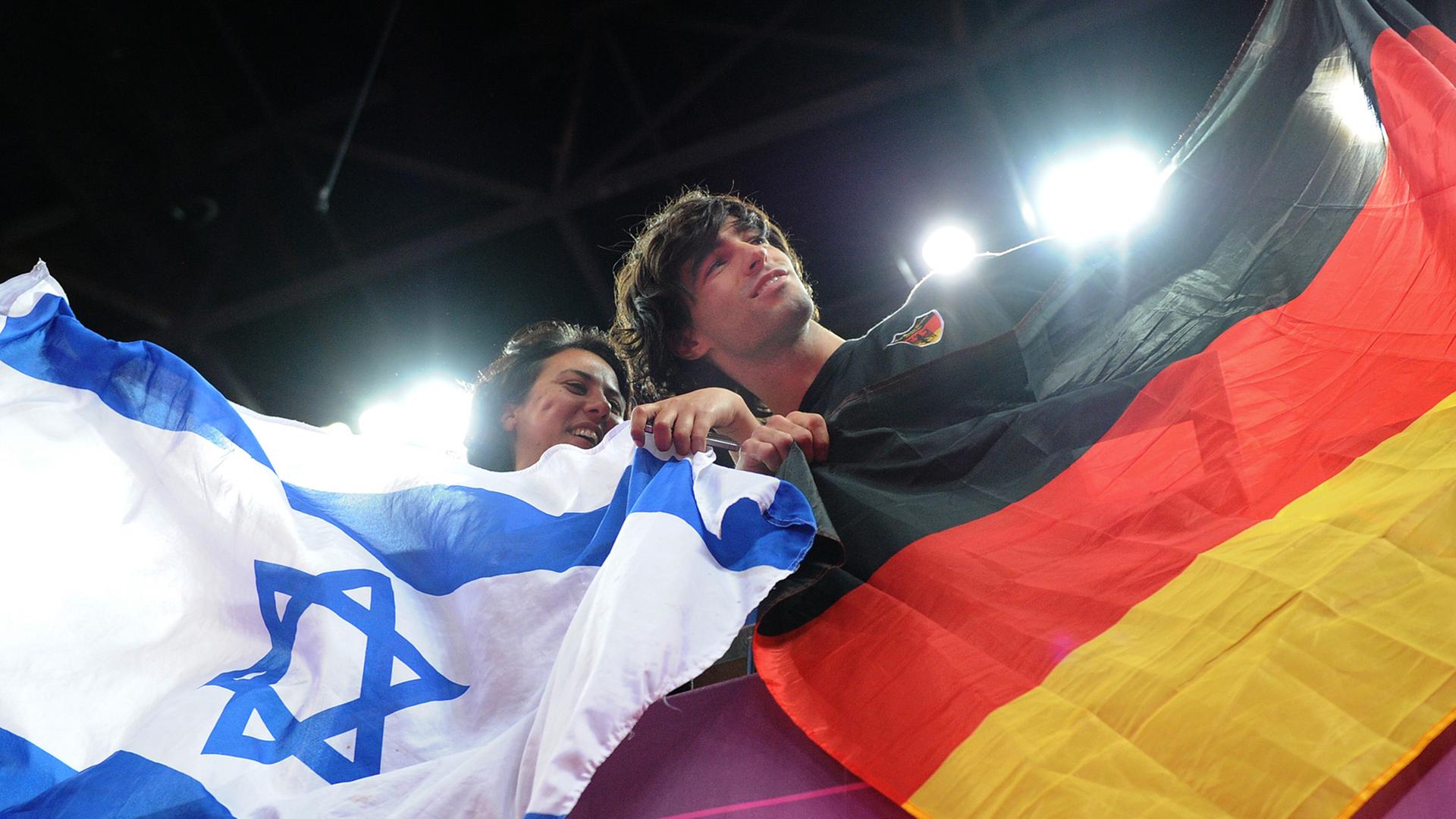 Eine Frau und ein Mann mit einer israelischen und einer deutschen Flagge.