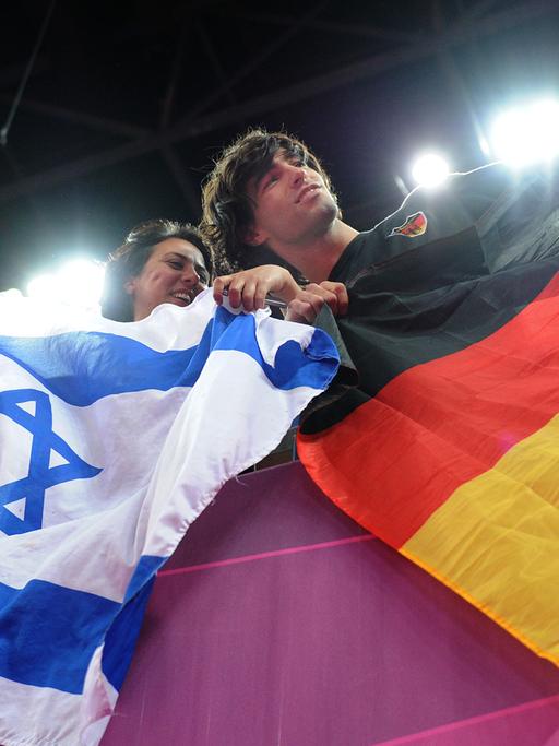 Eine Frau und ein Mann mit einer israelischen und einer deutschen Flagge.